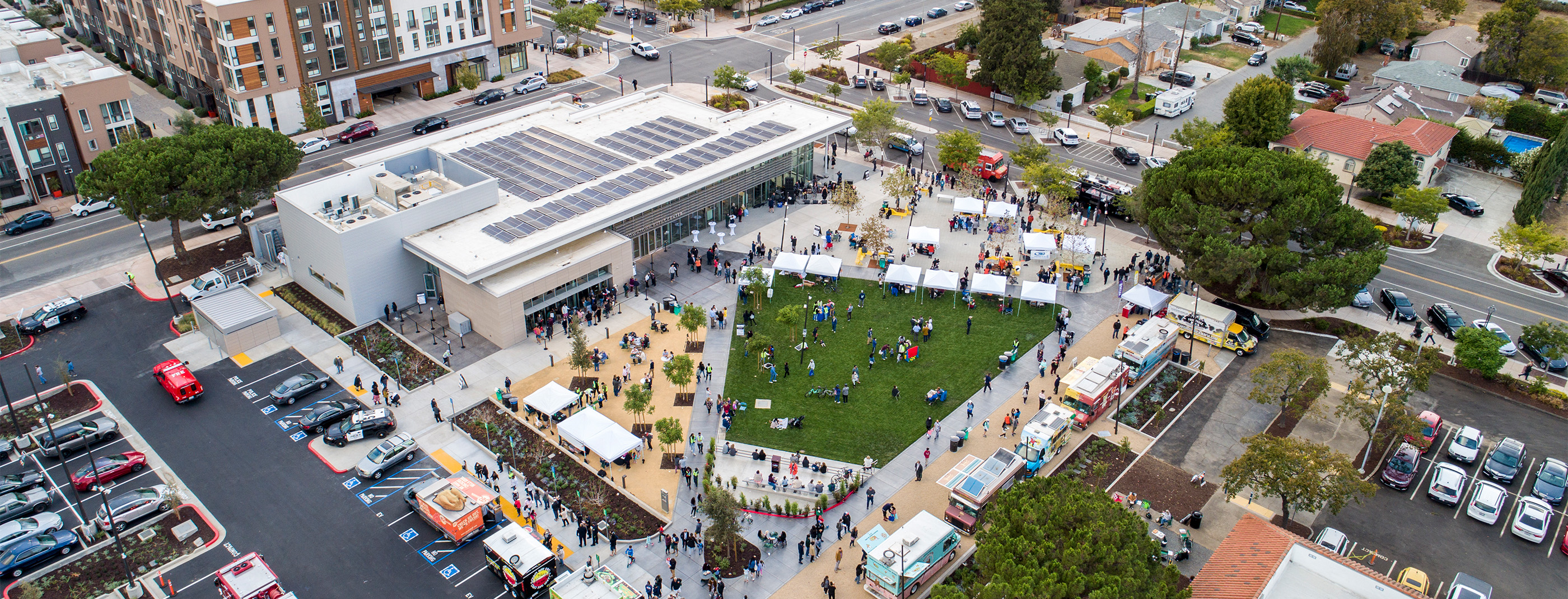 City of Fremont Downtown Event Center with PV array on top of building in front of plaza filled with people.