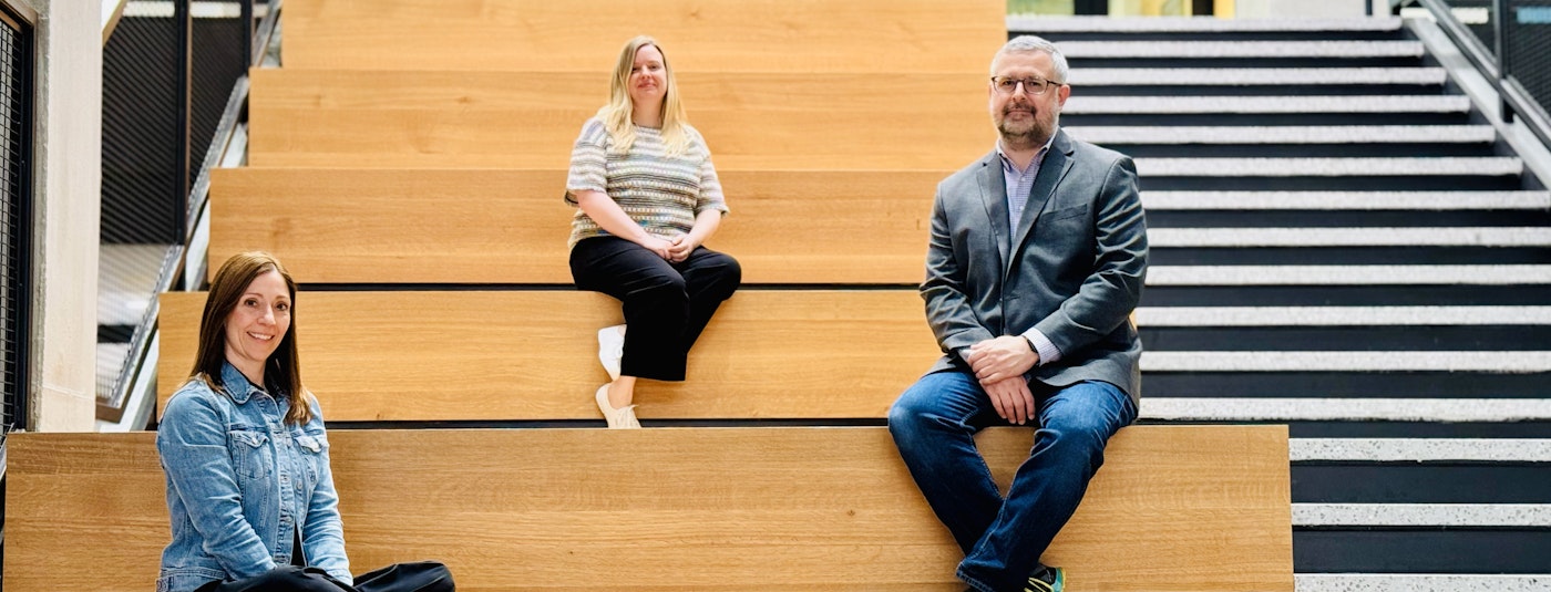 Three people sit on bleacher stairs. From left to right: Monica Reed, Project Manager, Pennsylvania State University; Erin Carlisle, Principal, STUDIOS Architecture; and Scott Myrick, Director of Operations, Bellisario Media Center at Penn State University