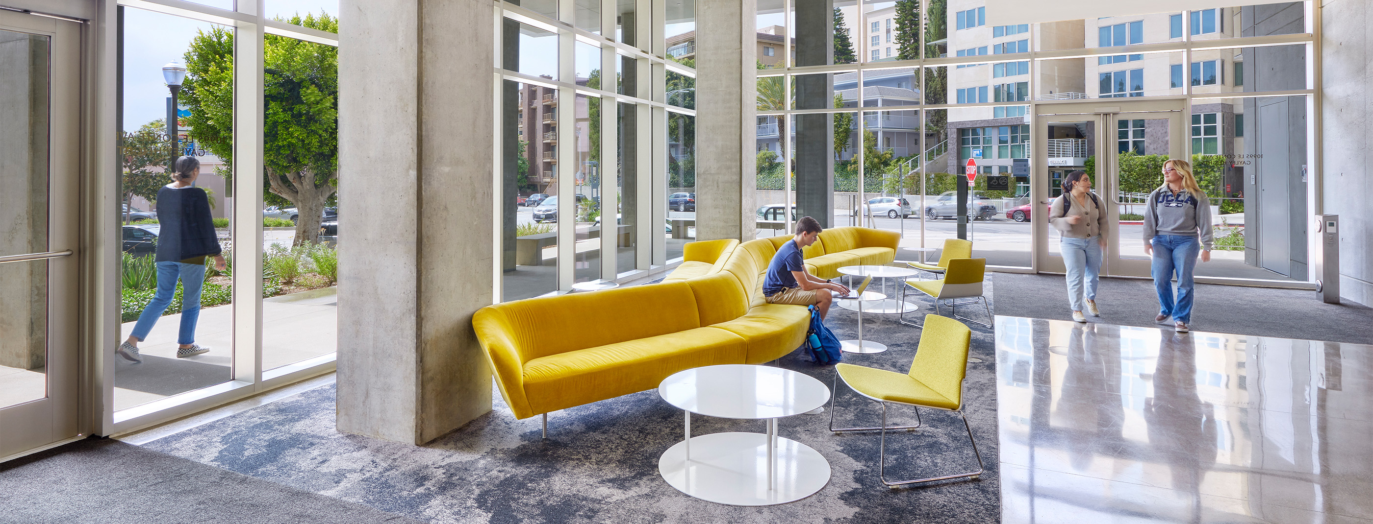 UCLA Gayley Heights Apartments ground-floor common area with soft seating, tables, and students.